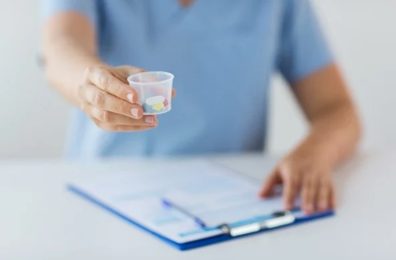 health care provider holding cup of pills