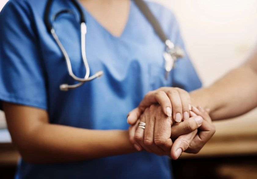 health care provider's hand holding resident's hand