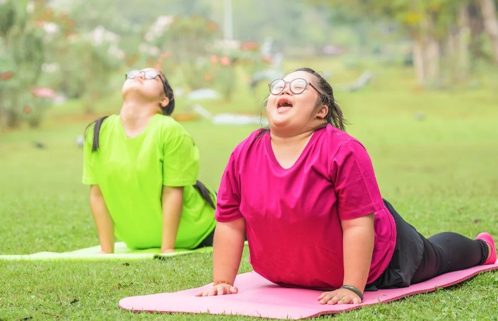 two girls with I/DD doing yoga outside