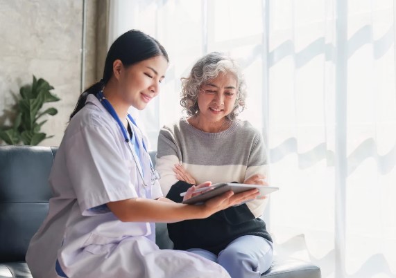 woman and caregiver sitting side by side reading something