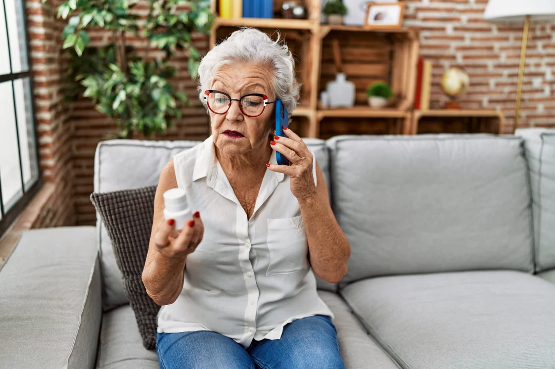 Elderly woman looking at medication bottle